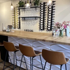 Bar with stool seating and wine bottles displayed on wall