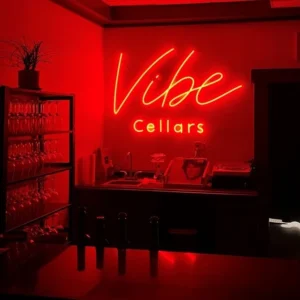 Red neon sign reading "Vibe Cellars"