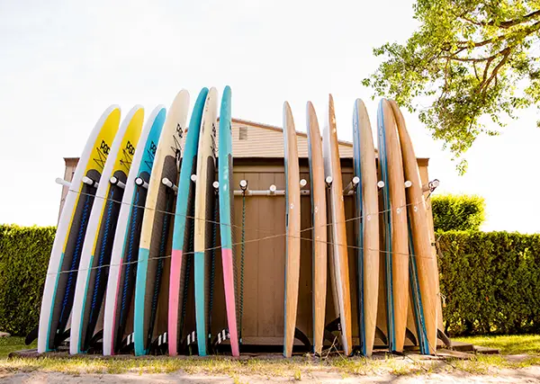 A bunch of paddle boards leaning up against the rental shack