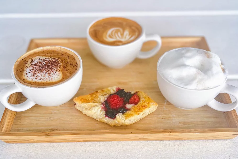 Three coffees on a board with fruit pastry